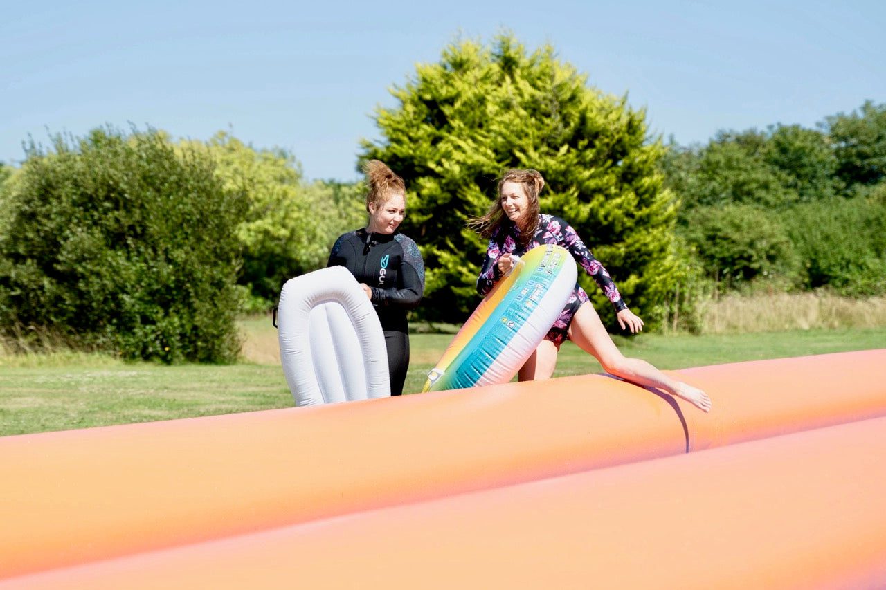 Girls preparing to slide on the giant inflatable at Cornwall Slip and Slide, Atlantic Reach Resort near Newquay