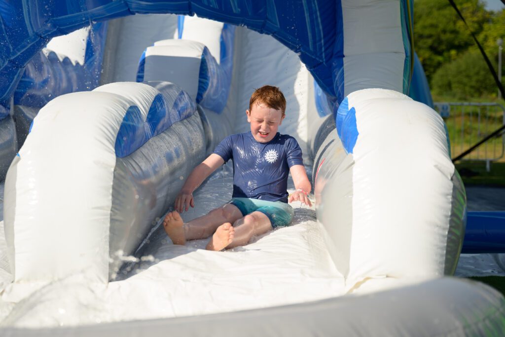 Boy enjoying the giant inflatable slide at Cornwall Slip and Slide, Atlantic Reach Resort near Newquay