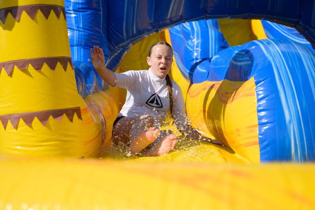 Girl enjoying the giant inflatable slide at Cornwall Slip and Slide, Atlantic Reach near Newquay