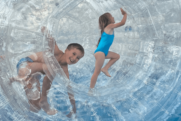 Two kids having fun in a zorb at Cornwall Slip and Slide, Atlantic Reach Resort near Newquay